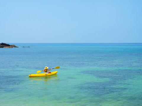 Asian tourist on yellow Kayak boat in tropical island blue sea bright sun in summer. Koh Kood - Thailand
