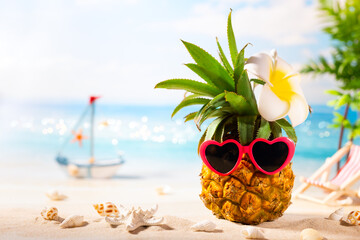 Summer vacation beach concept. Pineapple with sunglasses in heart form. Hipster fruit on the sand against of sea. Summer party idea.