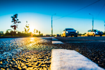 Sunset after rain, the headlights of the cars traveling on the highway. Wide angle view of a close-up from the level of the dividing line