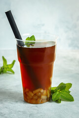 A cup of bubble tea with mint on grey background