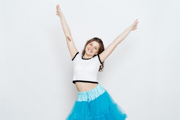 Cheerful teenager girl with curly hair wearing blue fluffy skirt and white t shirt posing on white background. Emotions