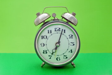 Old vintage alarm clock close up on green background