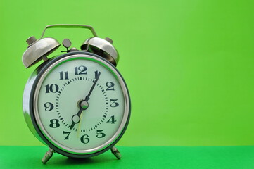 Old vintage alarm clock close up on green background