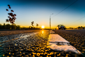 Sunset after rain, the car is moving on the highway. Wide angle view of a close-up from the level of the dividing line