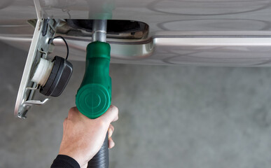 Gas station worker filling up bronze pickup truck tank (Top View). Closeup hand holding green gas...