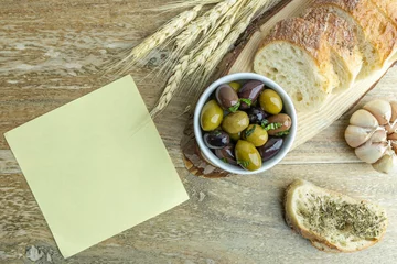 Foto op Plexiglas Pickled olives, rustic bread, empty notebook paper on wooden background. Mediterranean snacks. Rustic lunch.  © irina
