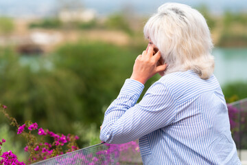 Middle-aged woman chatting on her phone on an outdoor patio
