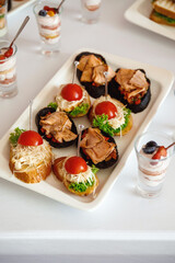 Canapes with cheese, tomatoes, meat and lettuce on a white festive table