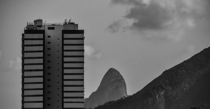 A black and white view of a residential building in Leme district and the Cabritos and Dois Irm&atilde;os rocky outcrops, Rio de Janeiro, Brazil