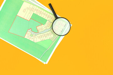 Choose a building plot of land for house construction, real estate office desk with map and magnifying glass background, top view