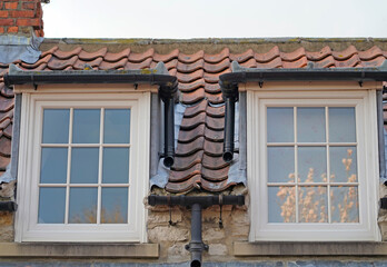 Old windows, tiled rood and reflection of tree in the window 