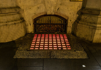 A red light from a basement seeps up to the street
