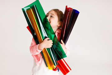 Little girl hugging colored foil tubes and learning colors, early development and learning concept
