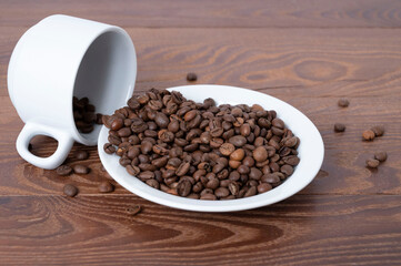 white cup and coffee beans on a saucer on a wooden background