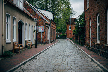 Fototapeta na wymiar scenic view of old street with cobblestones and brick wall houses in Leer / Germany