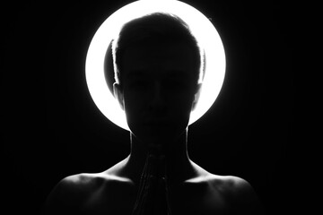 Silhouette of a man against the background of a shining halo. Beautiful collarbone in black and...