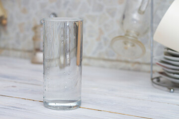 A glass full of clear water sits on the kitchen table. Copy space