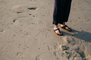 Woman standing on a beach wearing sandals
