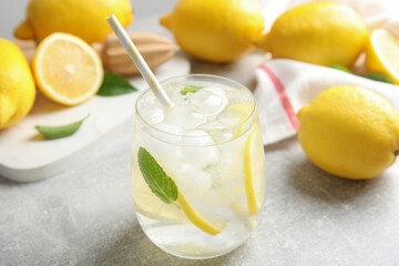 Glass of cold lemonade on light grey table, closeup