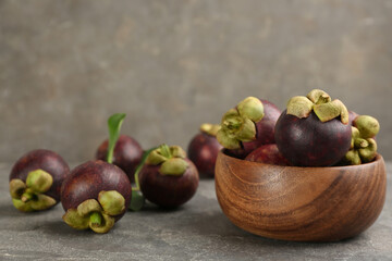 Fresh ripe mangosteen fruits on grey table. Space for text