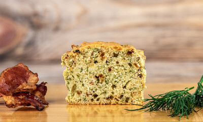 Sliced muffin with bacon and dill on a cutting board.