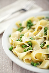 Tagliatelle pasta with cream and peas on a plate.