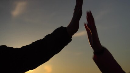hands of young men of guy and girl giving high fives at sunset. Two happy laughing best friends, man and woman, having fun and celebrating good luck and victory. Success. vacation adventure travel