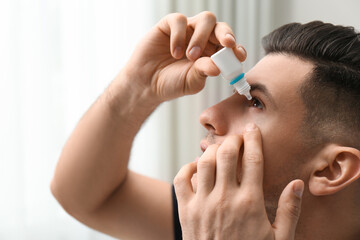 Man using eye drops on blurred background, closeup