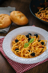 Spaghetti with tomato sauce, black olives and basil on a plate