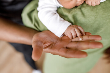 Small newborn baby holds hand of Afro American dad , close-up macro shot. A touching and wonderful moment. The concept of support, hope, love, connection and care, keep.