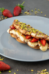 sandwich waffles with banana, strawberry and chocolate and pistachio on top