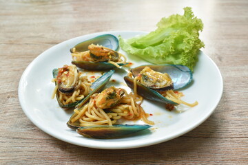 fried spicy spaghetti with basil leaf roll topping mussel dressing chili sauce on plate