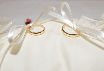 Close up view of pair of gold rings knotted to a white fabric cushion.