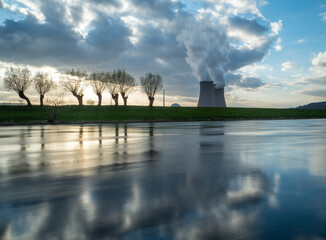 Nuclear power plant against sky by the river at sunset