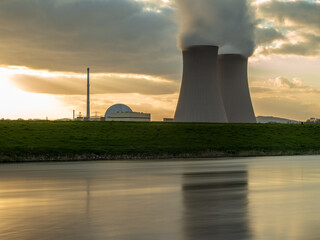 Nuclear power plant against sky by the river at sunset
