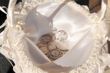Arras, coins that are symbolically used in a wedding ceremony placed inside a basket with white satin.