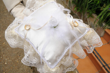 Gold and silver rings placed on a fabric cushion with floral and lace decoration.