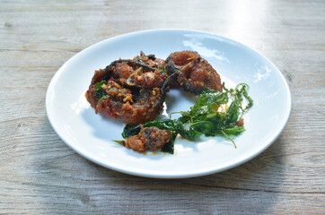 spicy stir fried crispy catfish curry with basil leaf on plate