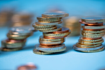 Piled up coins on blue backdrop. Euro coins from European Union. Currency and cash piled up to towers