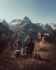 a girl enjoys a mountain landscape, sitting on a log, against the background of Mount Belalakaya