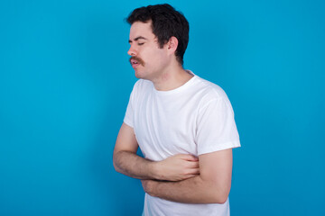 young handsome Caucasian man with moustache wearing white t-shirt against white background with sad expression covering face with hands while crying. Depression concept.