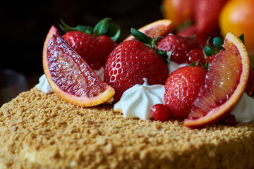 Honey cake garnished with strawberries, red orange and cream. Side View, close-up.