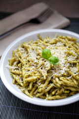 Pasta with pesto sauce and parmesan on a plate.