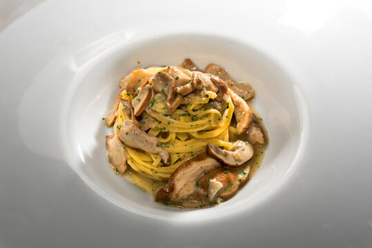 Tajarin with porcini mushrooms or Boletus edulis, fettuccine pasta from Alba, Langhe, Piedmont, Italy, close up in white dish