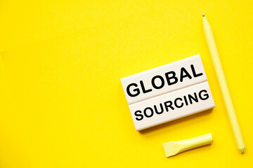 GLOBAL SOURCING. WOODEN BARS with informationon on the a yellow background desktop .