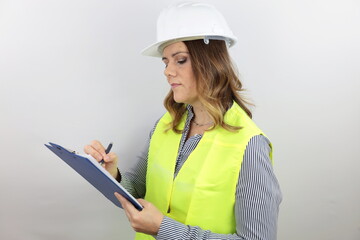 Female architect or engineer wearing safety helmet and reflecting jacket writing notes on flip board.