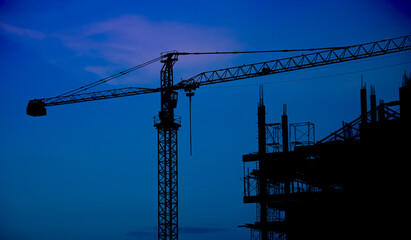 Construction of a tall building with cranes, sunlight. construction crane, building and blue sky at...
