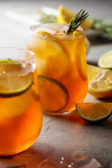 Iced tea with lemon, lime and ice garnished with rosemary twigs.