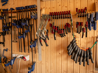 Carpentry workshop. Different clamps hanging on the wall.