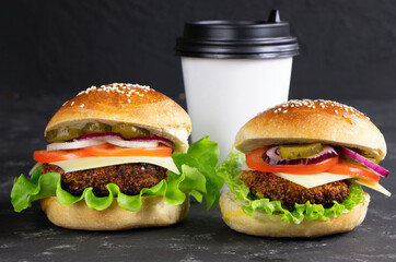 Cheeseburgers and cup of coffee on a black stone background. Hamburger with cheese. Burger isolated. Tasty Dinner.Copy space